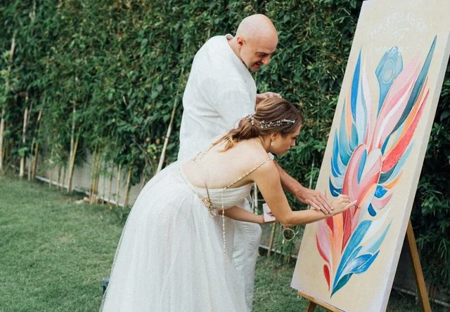 The couple painting a canvas at their reception